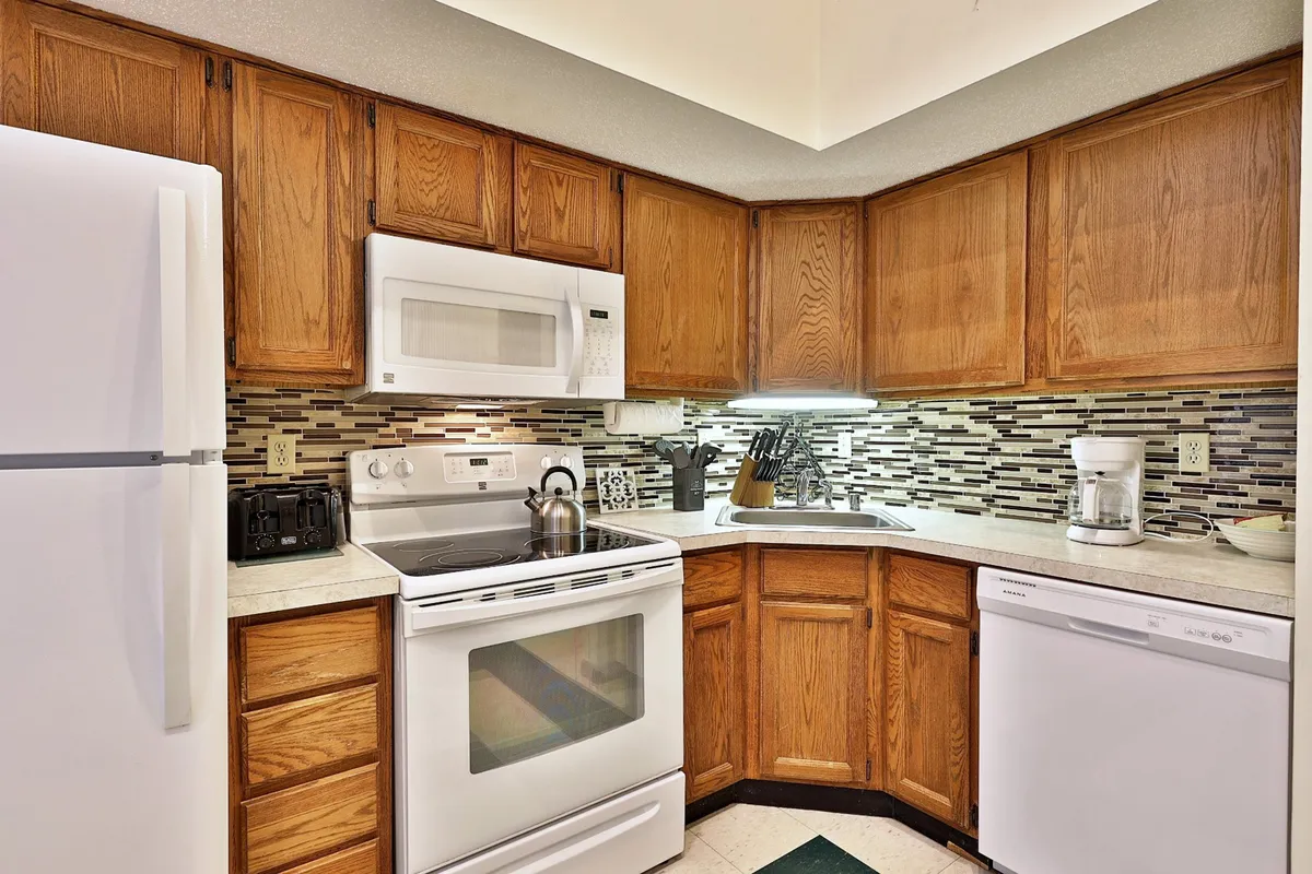 A view of the kitchen area with modern appliances, warm cabinetry, and a spacious countertop. The layout invites cooking, meal preparation, and gathering with friends or family. The design is warm, bright, and conducive to socializing.