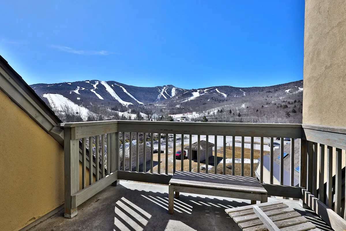 A serene balcony scene overlooking snow-covered mountains, with comfortable outdoor seating. The setting is tranquil, ideal for sipping coffee or watching sunsets, with the majestic landscape as a backdrop.