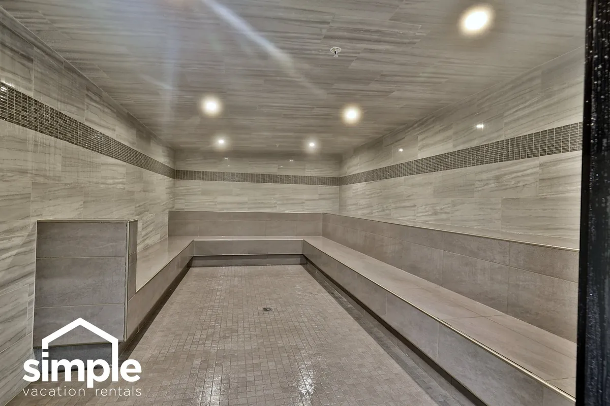 A tranquil spa area featuring smooth tiled benches, ambient ceiling lights, and textured wall tiles, evoking a serene and rejuvenating environment ideal for relaxation and socializing with friends or family.