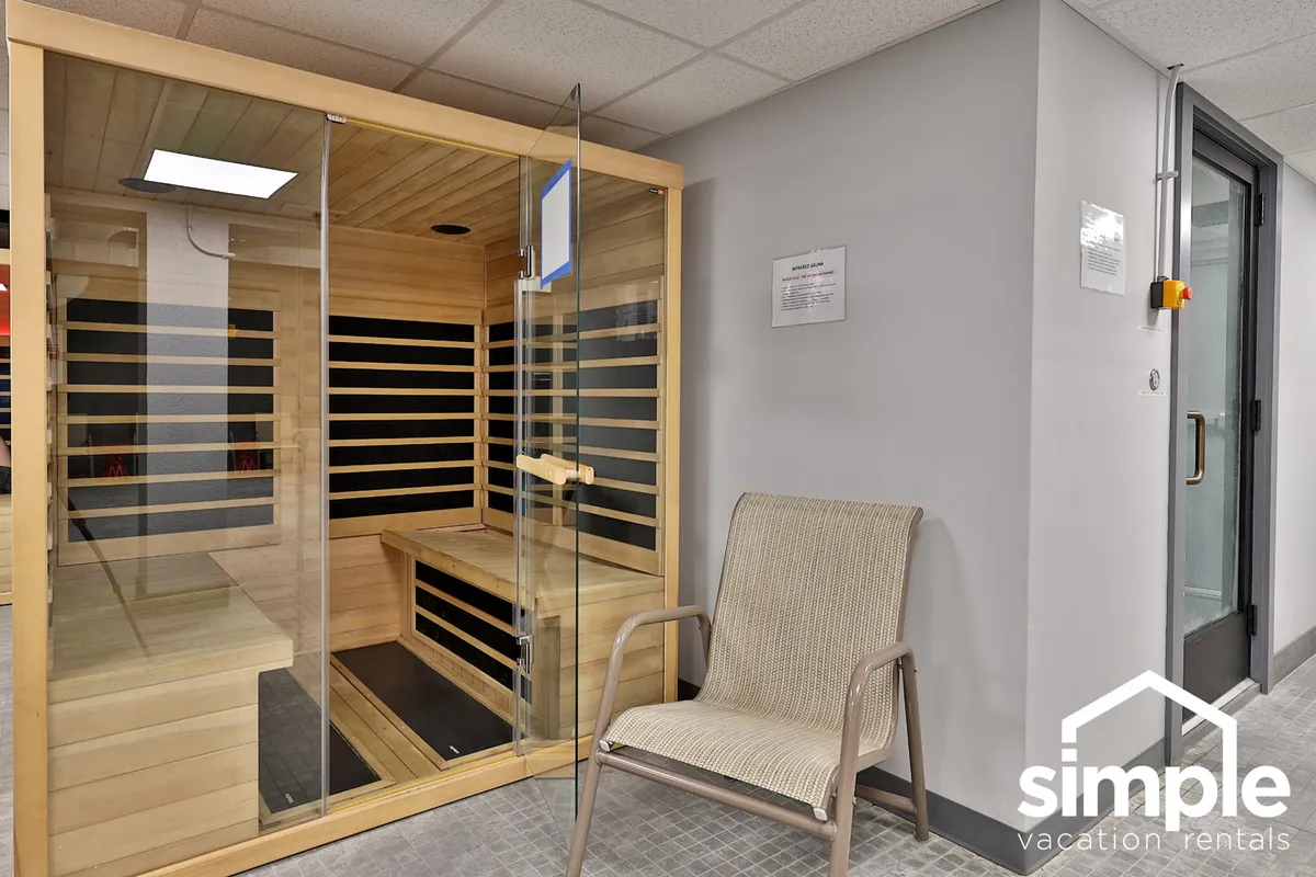 A serene wellness area featuring a glass sauna, a wooden bench, and a comfortable chair. The clean, modern design and tranquil atmosphere make it an ideal space for post-workout or après-ski rejuvenation.